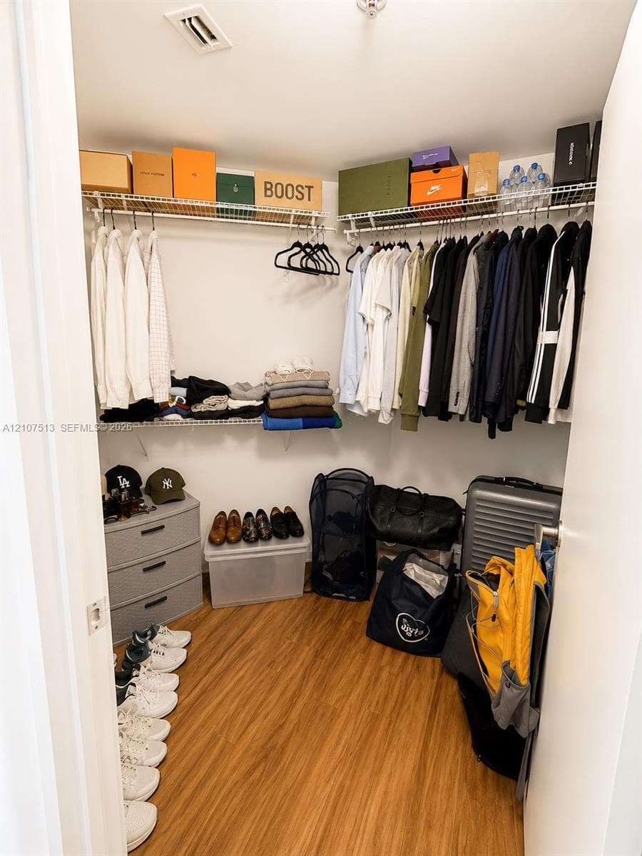 Walk-in closet featuring wood-finish flooring and dual-level wire shelving