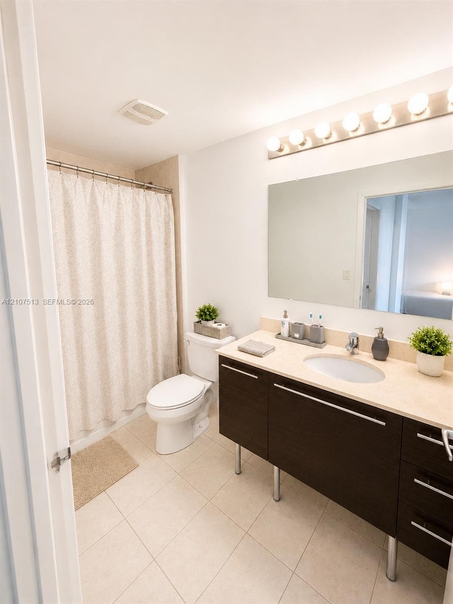 Bathroom featuring a dark wood-finish vanity with metal legs, a solid surface countertop with an integrated oval sink, a large wall-mounted mirror, and a multi-bulb light fixture