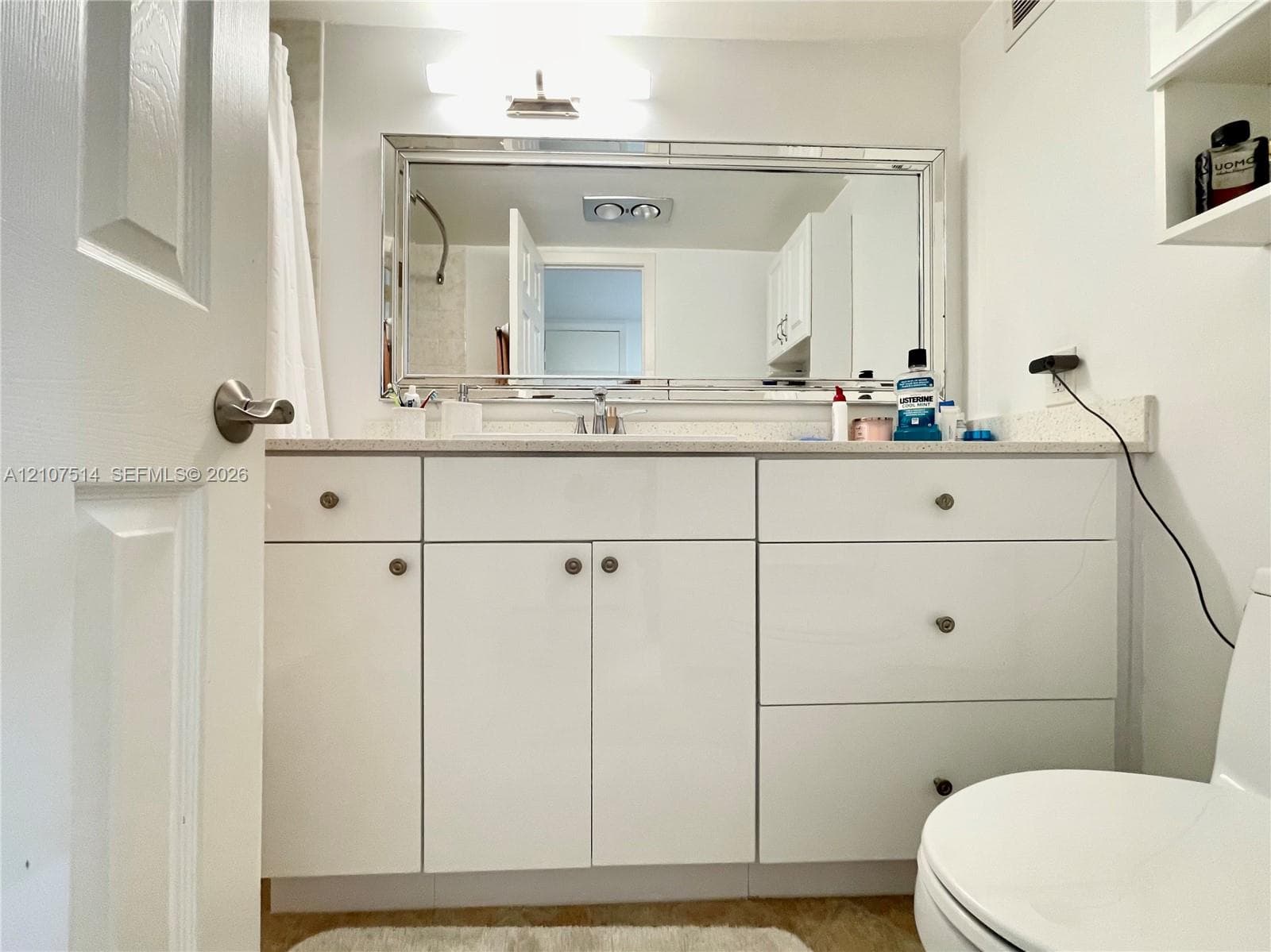 Bathroom vanity with white cabinetry, flat-panel doors, integrated drawers, stone-finish countertop, and a large rectangular mirror