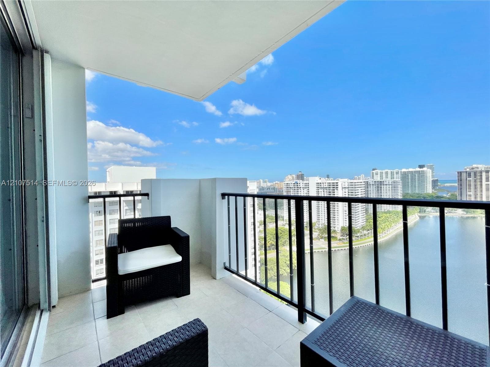 Covered balcony featuring tile flooring and a black metal railing