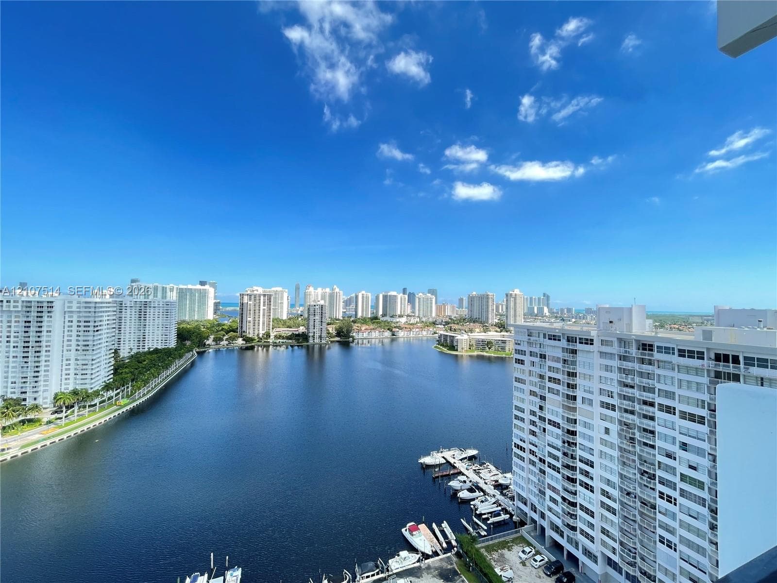 High-rise balcony perspective featuring expansive water frontage, boat slips, and a cityscape skyline