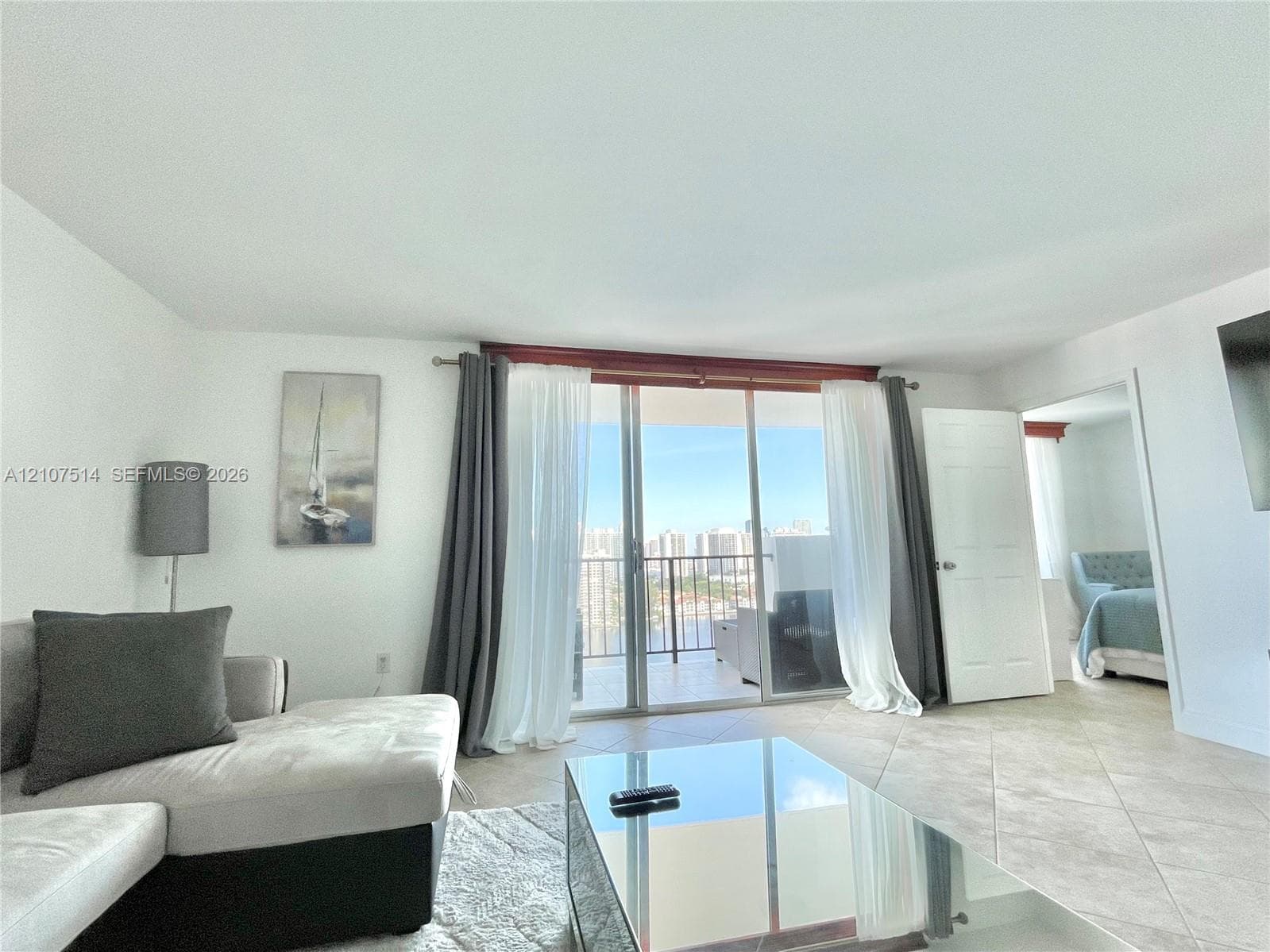 Sliding glass doors featuring floor-to-ceiling panels, neutral tile flooring, and a private balcony with metal railings