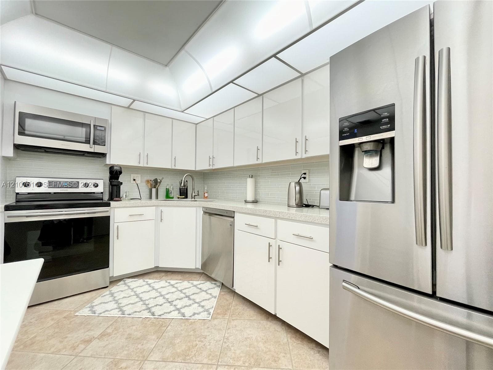 Kitchen featuring white gloss cabinetry, stone-finish countertops, stainless steel appliances, recessed ceiling lighting, and tiled flooring
