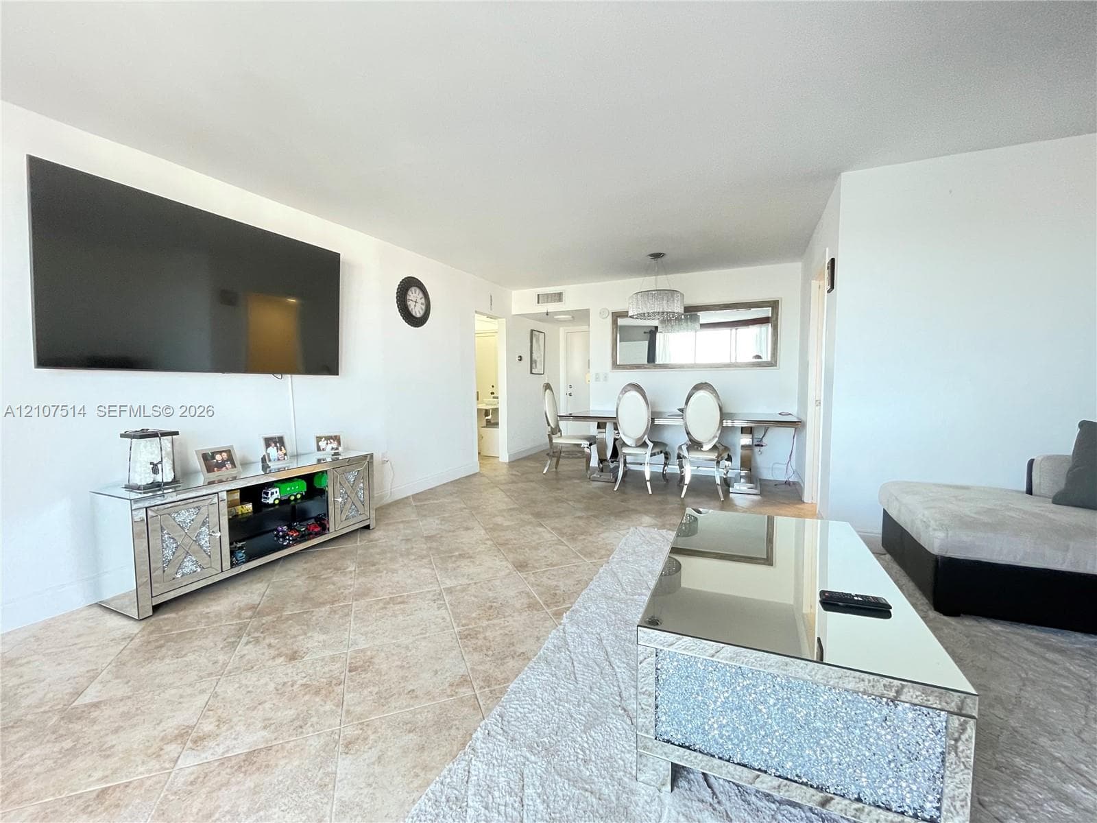 Open-concept floor plan featuring neutral stone-finish tile flooring throughout and a modern drum-style chandelier fixture