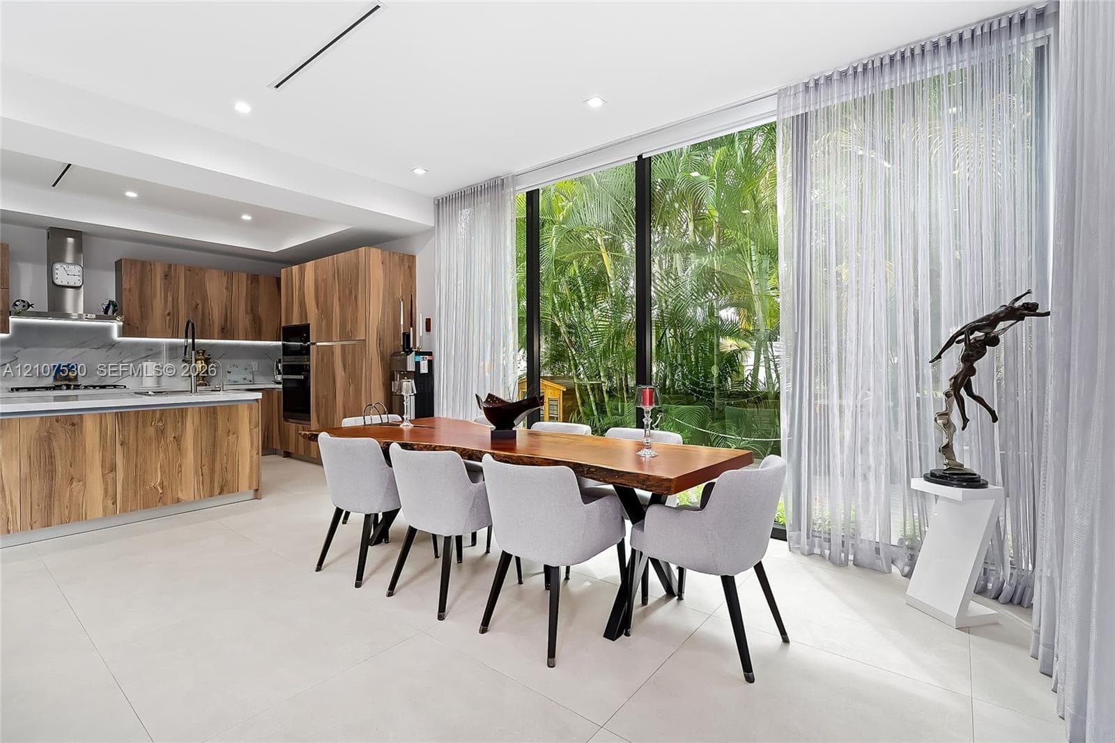 Modern kitchen featuring custom wood-finish cabinetry, stone slab backsplash, integrated built-in appliances, and floor-to-ceiling glass windows