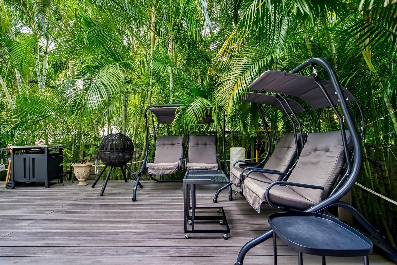 Outdoor deck featuring wood-finish composite planking and mature tropical foliage