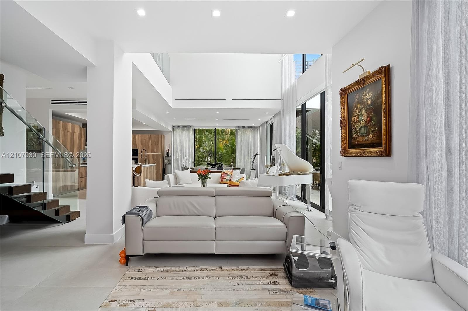 Double-height ceiling, open-concept floor plan, recessed lighting, staircase with glass railings, and floor-to-ceiling windows