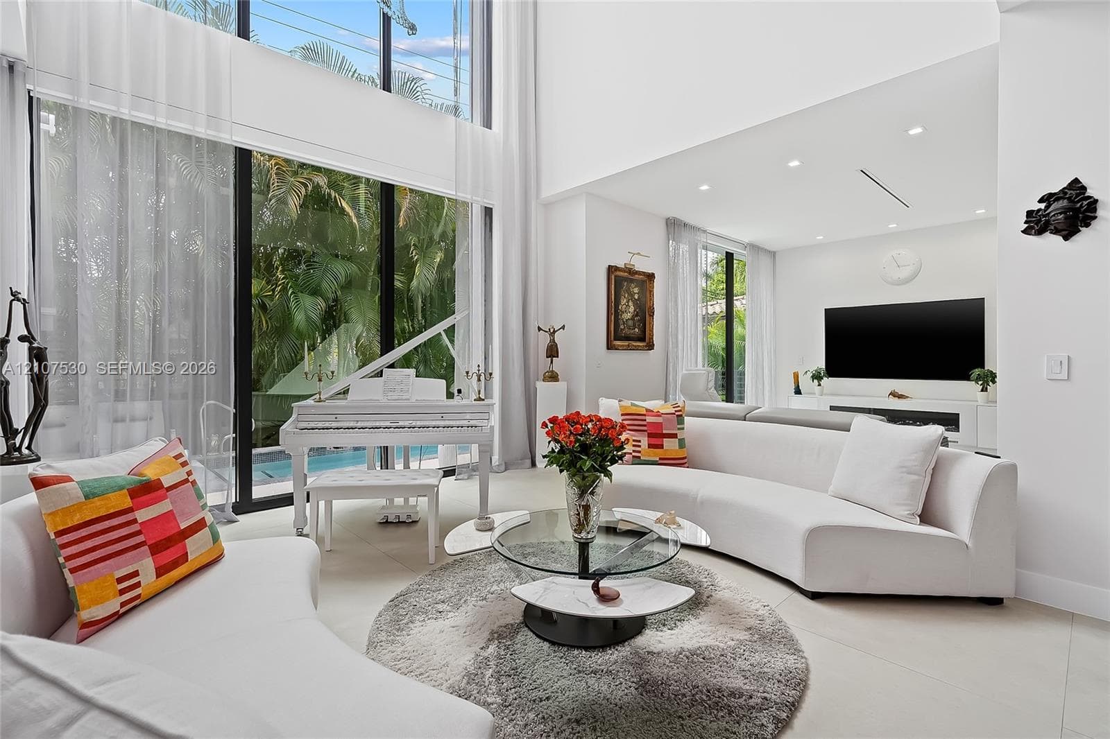 Double-height ceilings, floor-to-ceiling glass wall, recessed lighting, and large-format tile flooring
