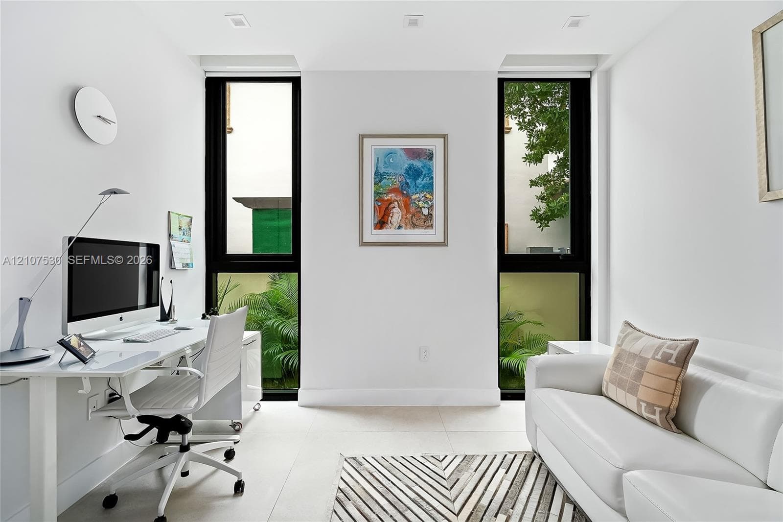 Bright room featuring large, floor-to-ceiling windows with black frames, recessed ceiling lighting, and light-toned tile flooring