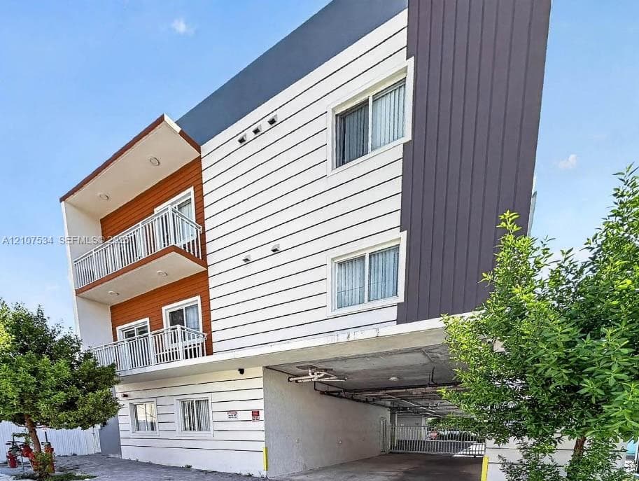 Contemporary multi-story exterior featuring a mix of horizontal white siding, dark vertical panels, and wood-finish accents