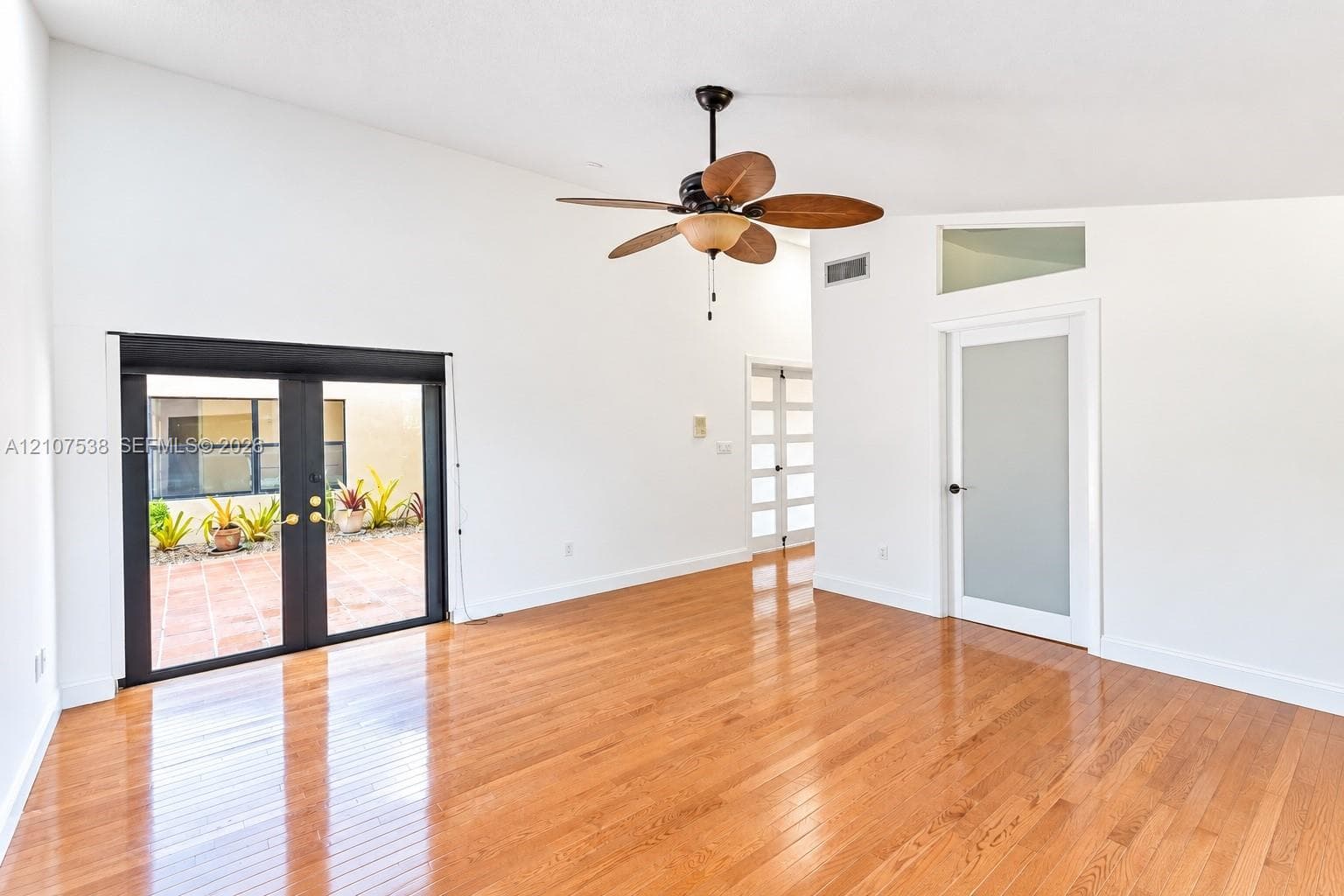 Vaulted ceilings, wood-finish flooring, French doors with exterior access, and a frosted glass panel door with an integrated transom window