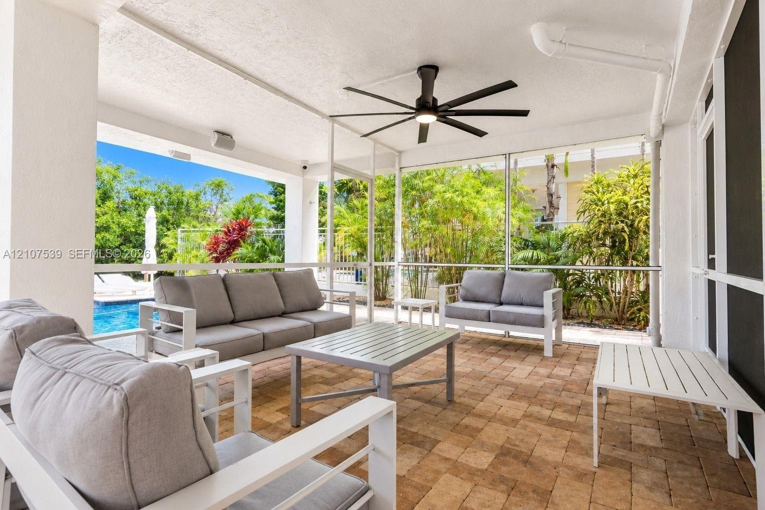 Covered screened lanai featuring paver flooring, a ceiling fan with integrated lighting, and structural columns