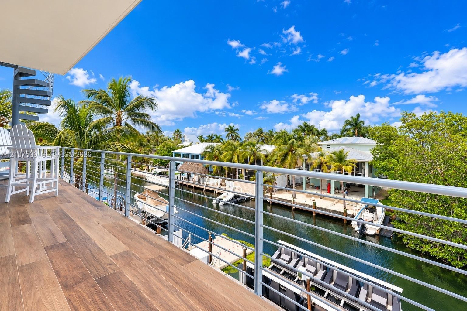 Elevated deck with wood-finish flooring, metal cable railing, and a spiral staircase