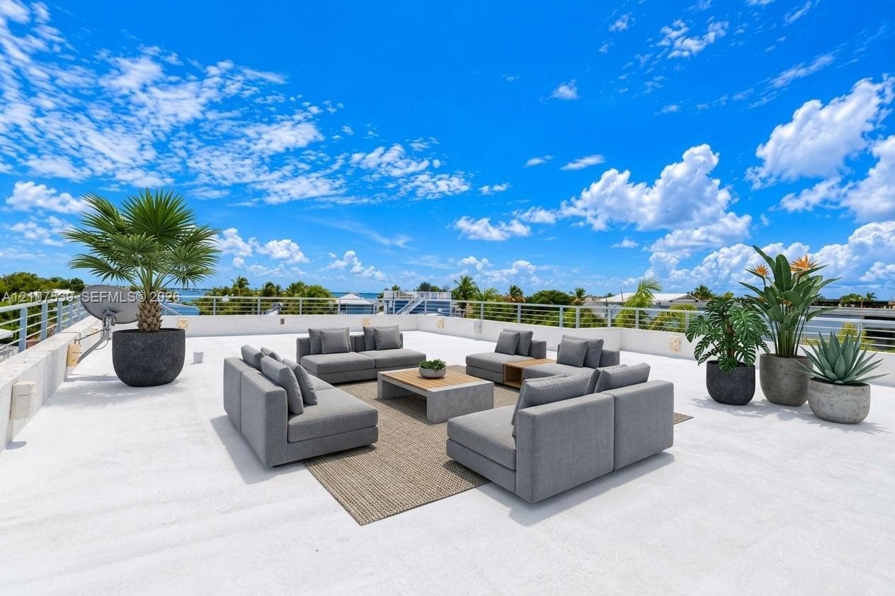 Expansive rooftop terrace featuring white flat surfacing, horizontal cable railings, and wall-mounted exterior lighting