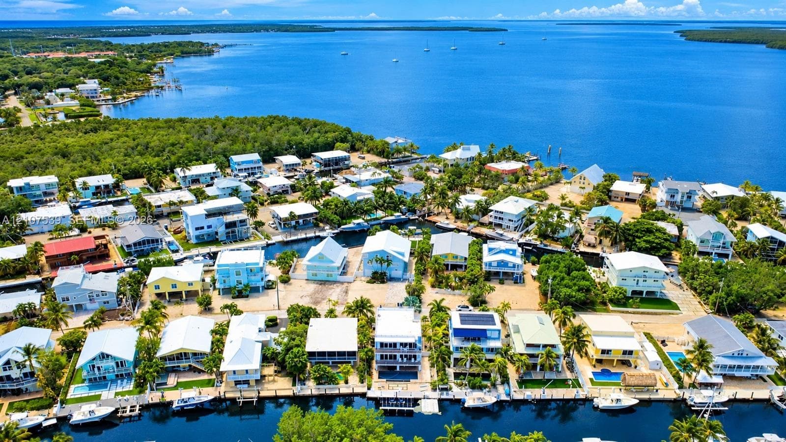 Aerial perspective of a coastal residential community featuring deep-water canal access, private boat docks, and surrounding open water
