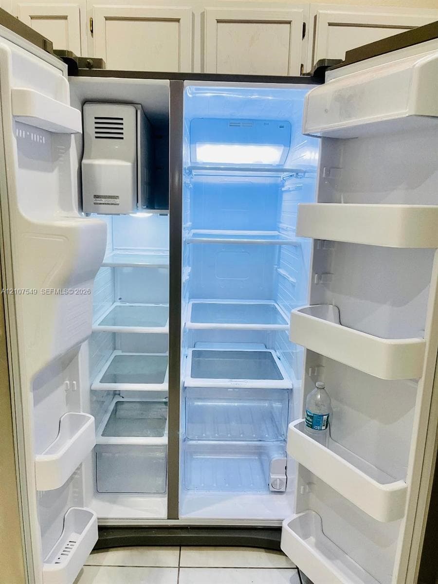 Side-by-side stainless steel refrigerator featuring adjustable glass shelving, clear crisper drawers, integrated door storage, and a built-in ice dispenser