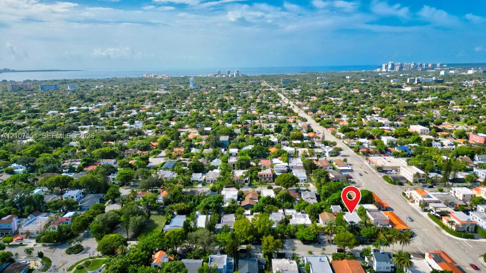 Aerial perspective of the property featuring dense mature tree coverage, proximity to regional thoroughfares, and a coastal landscape setting