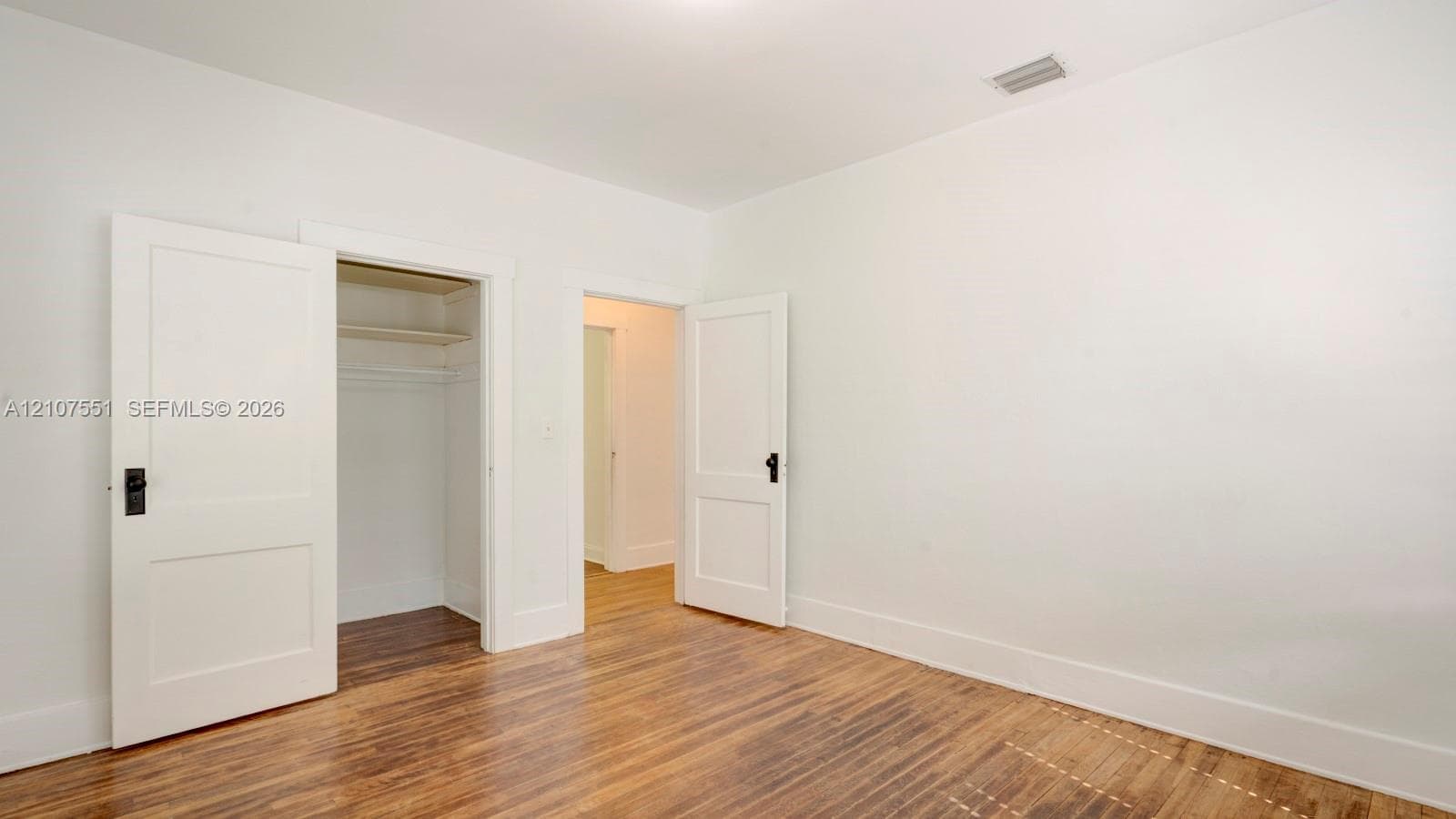 Wood-finish flooring, two-panel interior doors with matte black hardware, and integrated closet shelving