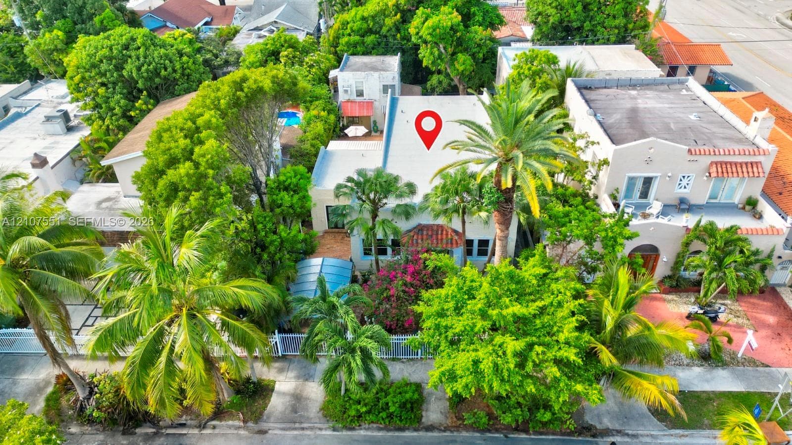 Aerial perspective of a detached residence featuring a pitched roof, terracotta-tiled accents, mature palm trees, and established landscaping