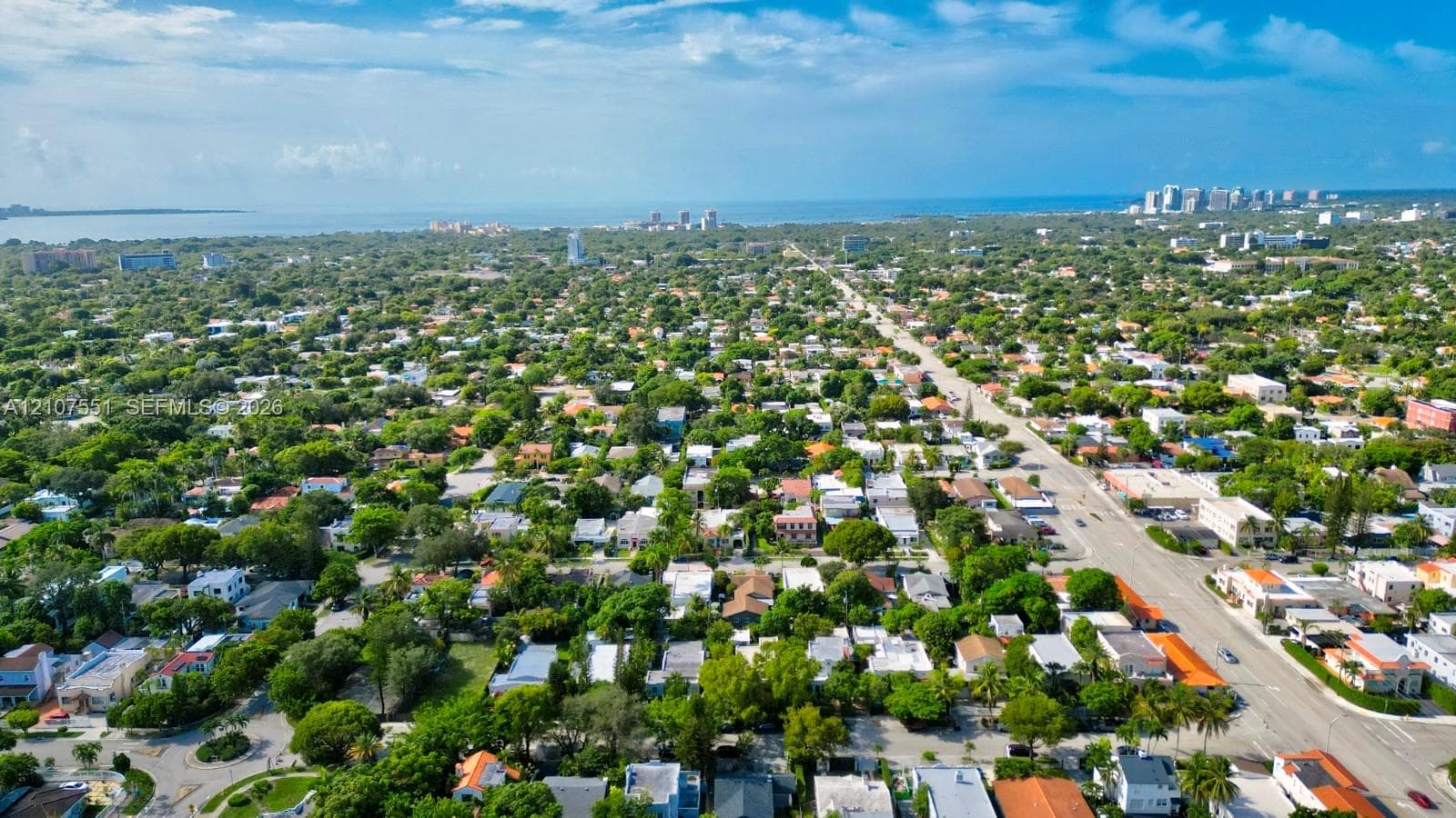 Aerial perspective featuring mature tree canopy, dense residential landscaping, and coastal proximity