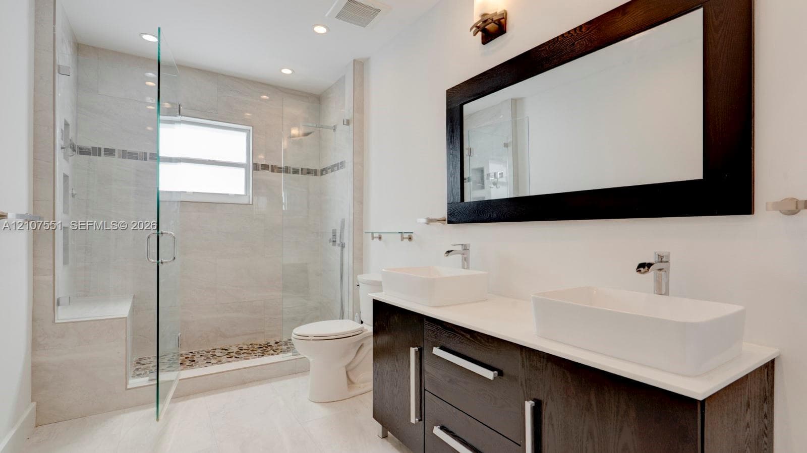 Double vanity featuring rectangular vessel sinks, dark wood cabinetry, and a stone countertop