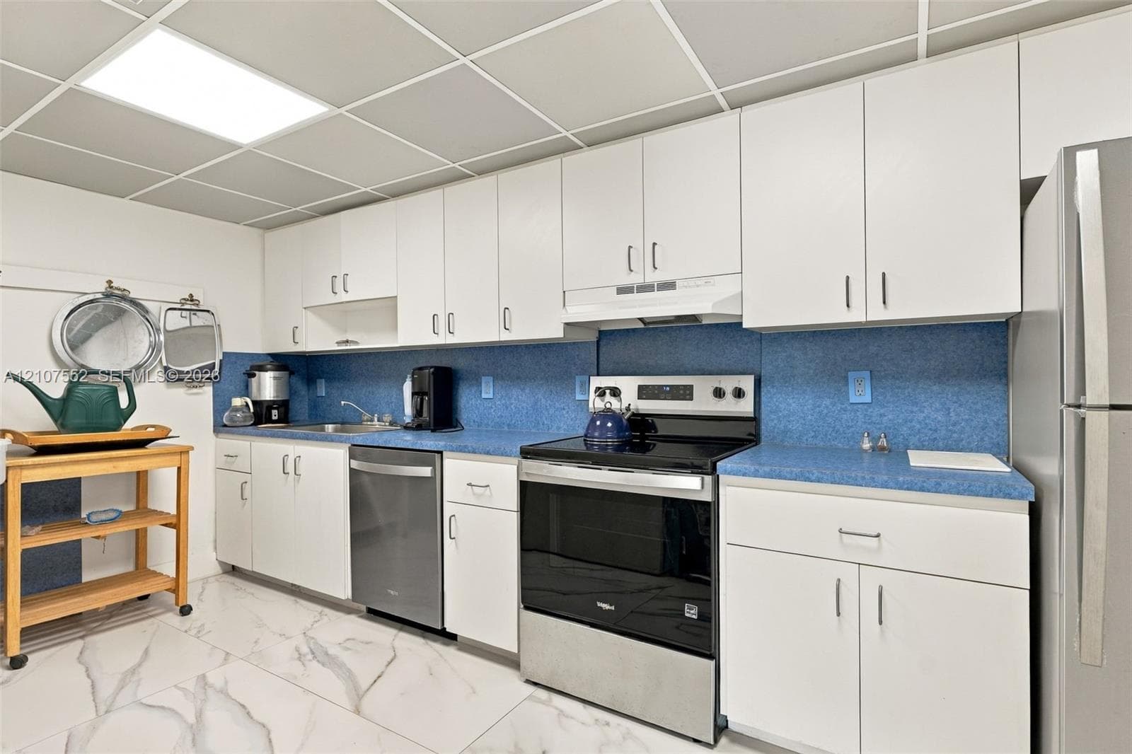Kitchen featuring white cabinetry, blue countertops, stainless steel appliances, and tile flooring