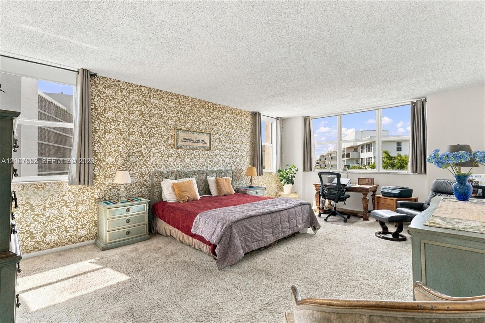 Expansive room featuring patterned accent wall, plush carpeting, and floor-to-ceiling windows