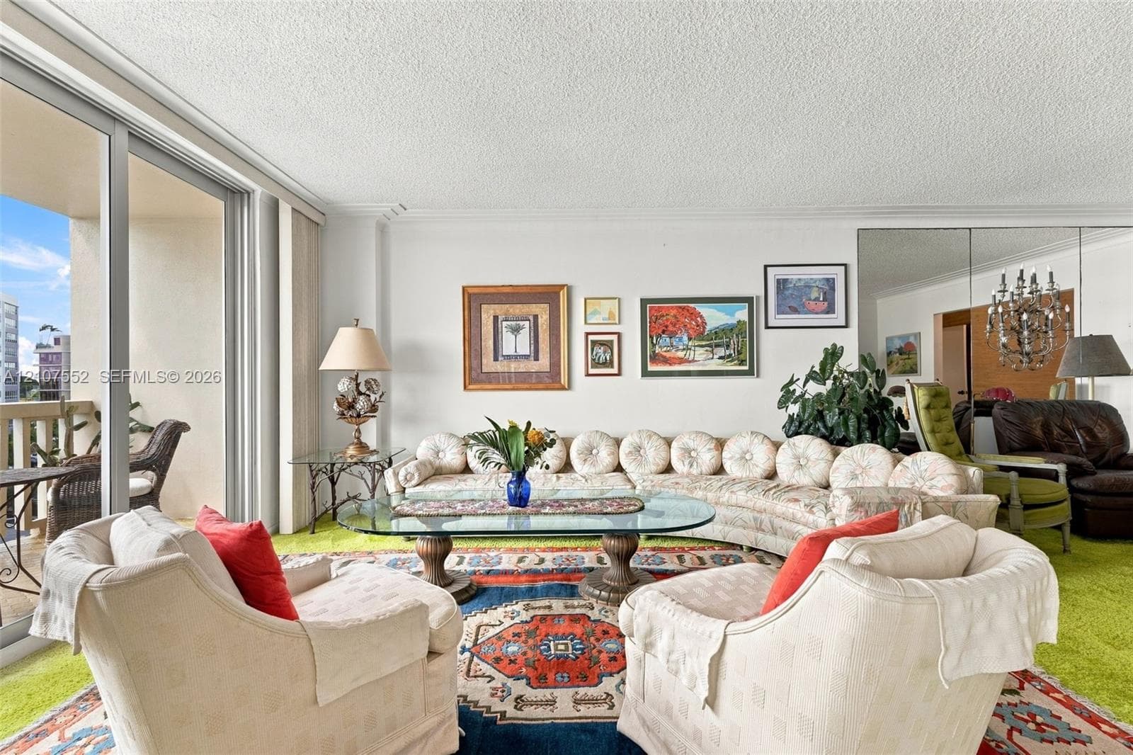 Living area featuring floor-to-ceiling glass sliding doors, private balcony access, and floor-to-ceiling mirrored wall panels
