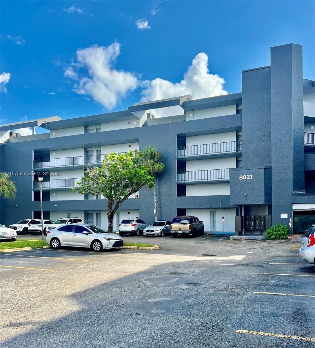 Multi-story exterior featuring a contemporary blue facade, private balconies, and dedicated surface parking