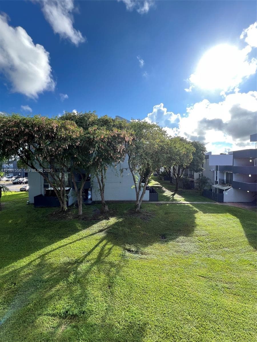 Expansive grassy common area featuring mature trees and established landscaping