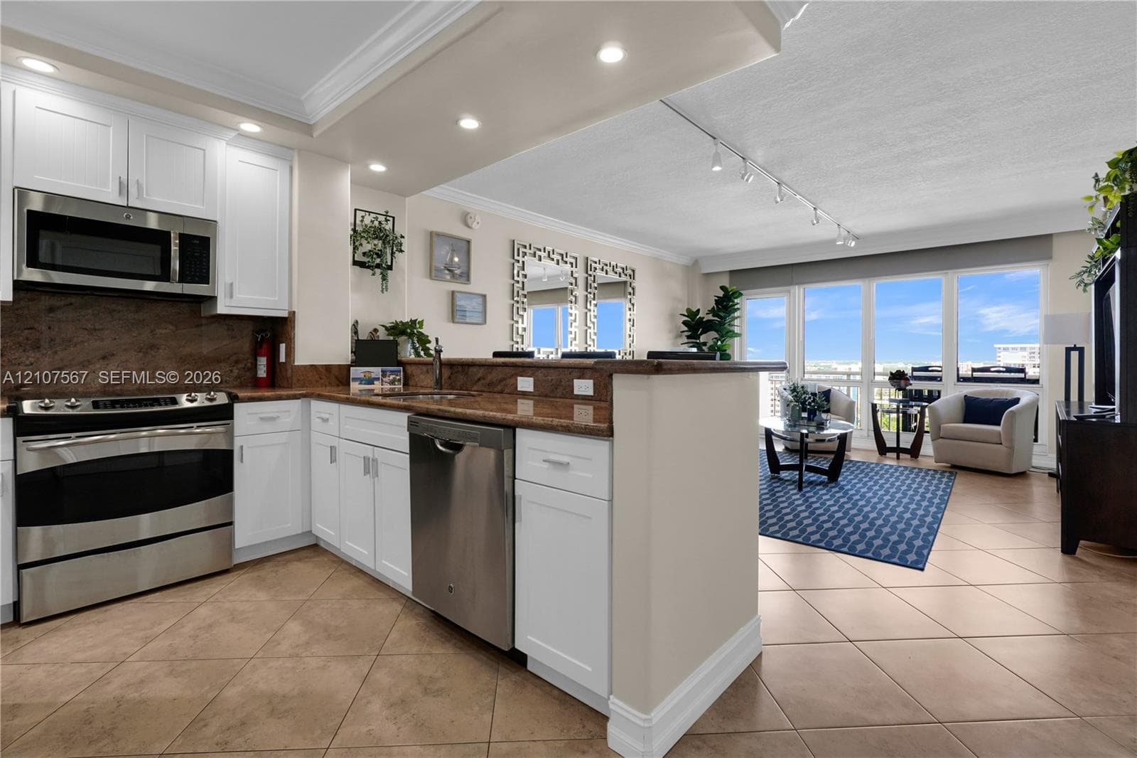 Kitchen featuring white cabinetry, stone countertops, stainless steel appliances, tile flooring, and track lighting