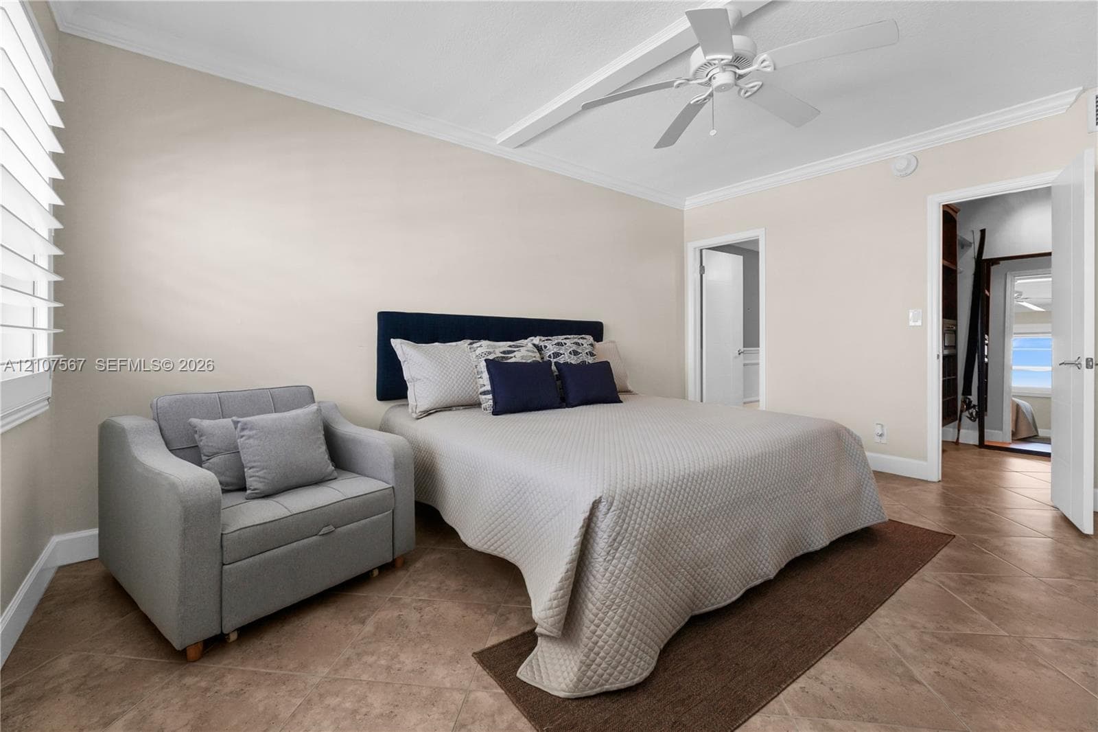 Neutral-toned walls with crown molding, diagonal tile flooring, multi-blade ceiling fan, and white shutter window treatments