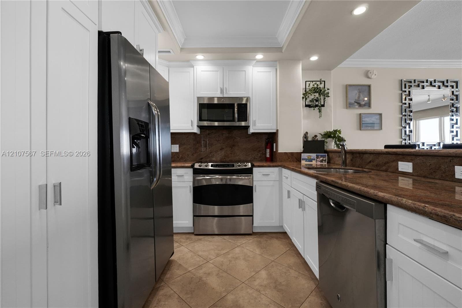 Kitchen featuring white shaker-style cabinetry, stainless steel appliances, stone-surface countertops, and tiled flooring