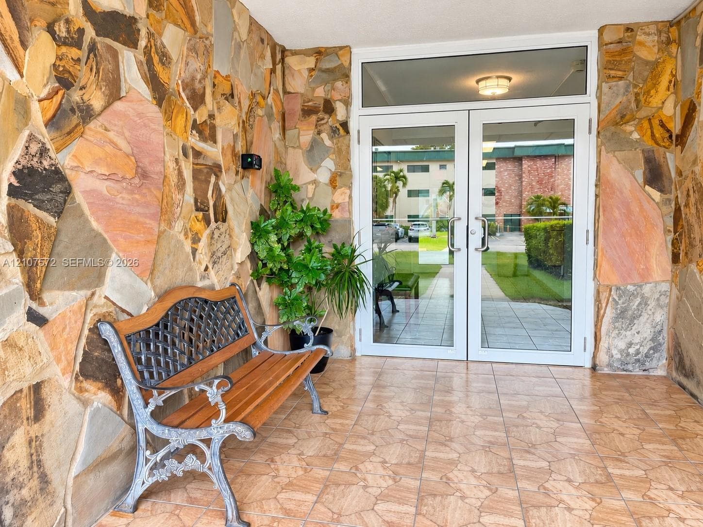 Entryway featuring natural stone veneer walls, ceramic tile flooring, and a double-door glass entrance with transom window