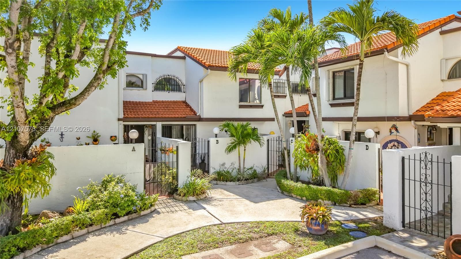 Exterior facade featuring white stucco walls, terracotta roof tiles, arched windows, and gated courtyard entries
