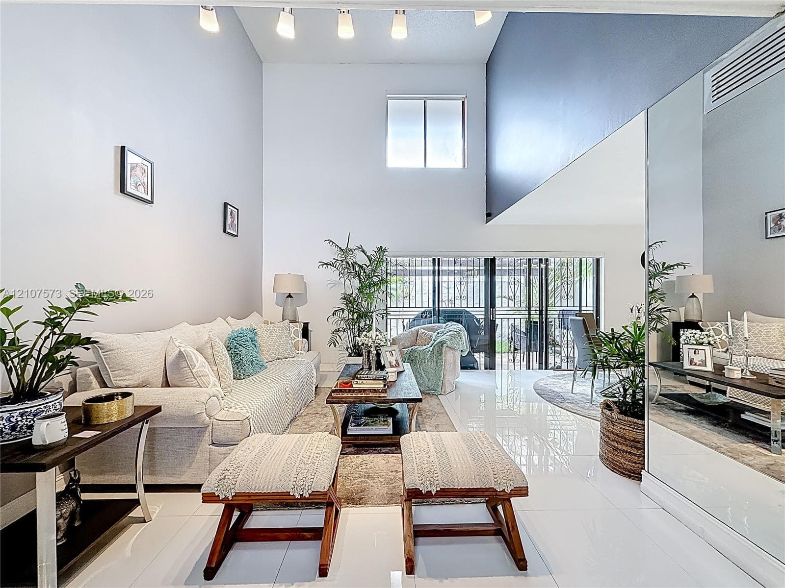 Double-height ceilings, polished tile flooring, full-wall mirrors, recessed track lighting, and sliding glass doors with exterior access
