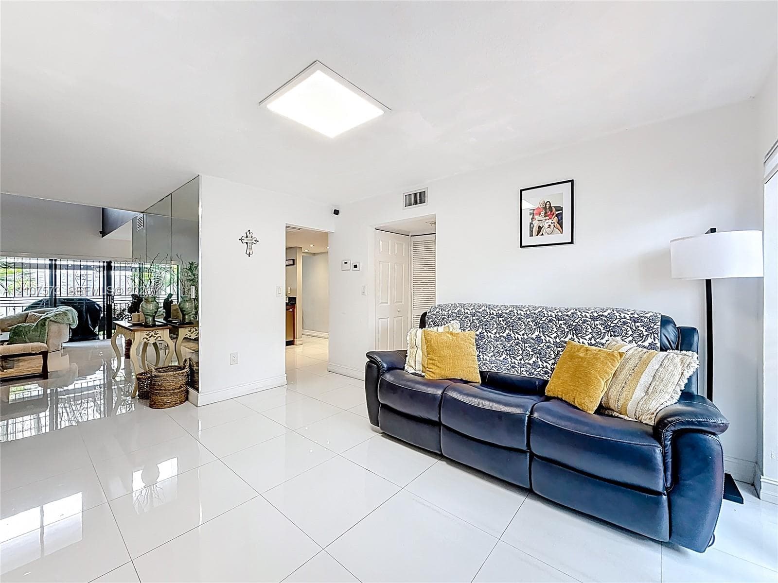 Polished porcelain tile flooring, mirrored wall accents, and recessed square lighting fixture