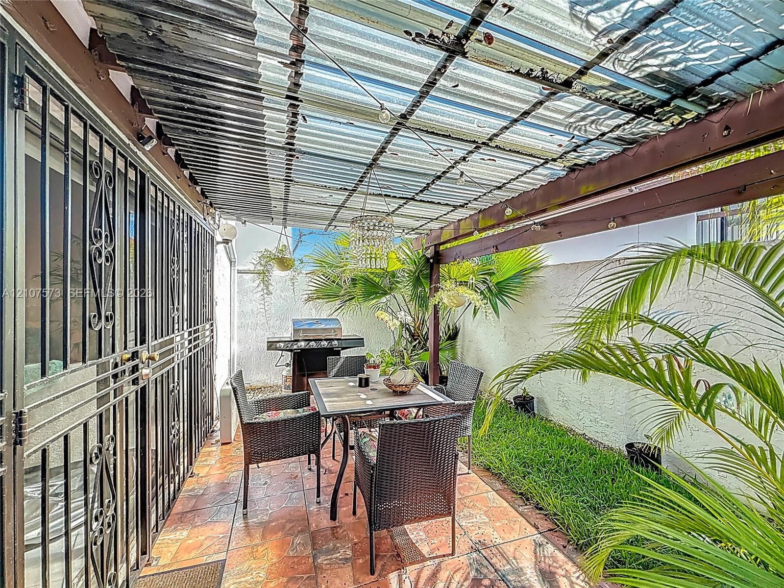 Enclosed patio featuring decorative metal security doors, tile flooring, and a privacy wall
