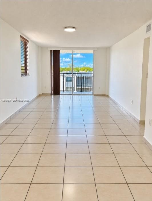 Open-concept interior featuring light-toned tile flooring, recessed ceiling lighting, horizontal window blinds, and sliding glass doors with balcony access