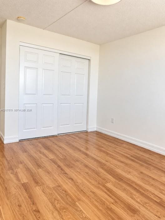 Room interior featuring wood-finish flooring and a closet with white six-panel sliding doors