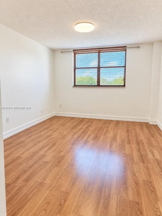 Interior space featuring wood-finish flooring, a flush-mount ceiling light fixture, and a window with horizontal blinds
