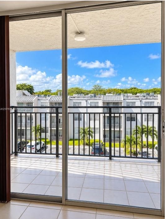 Private balcony featuring floor-to-ceiling sliding glass doors, neutral tile flooring, and black metal railings