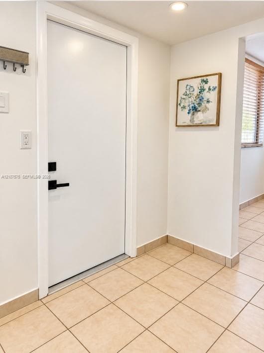 Interior entry featuring a white door with matte black hardware, recessed ceiling lighting, and neutral-toned ceramic floor tile