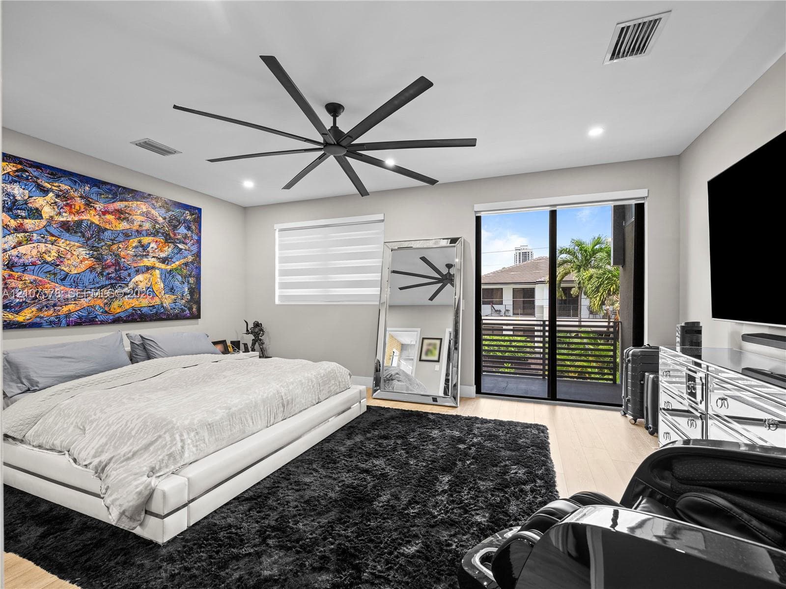 Expansive room featuring recessed lighting, a multi-blade matte black ceiling fan, wood-finish flooring, and a large sliding glass door providing access to a private balcony