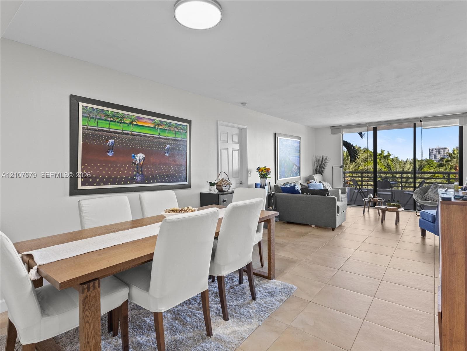 Open-concept interior featuring large-format neutral floor tile, expansive floor-to-ceiling windows, and access to a private balcony