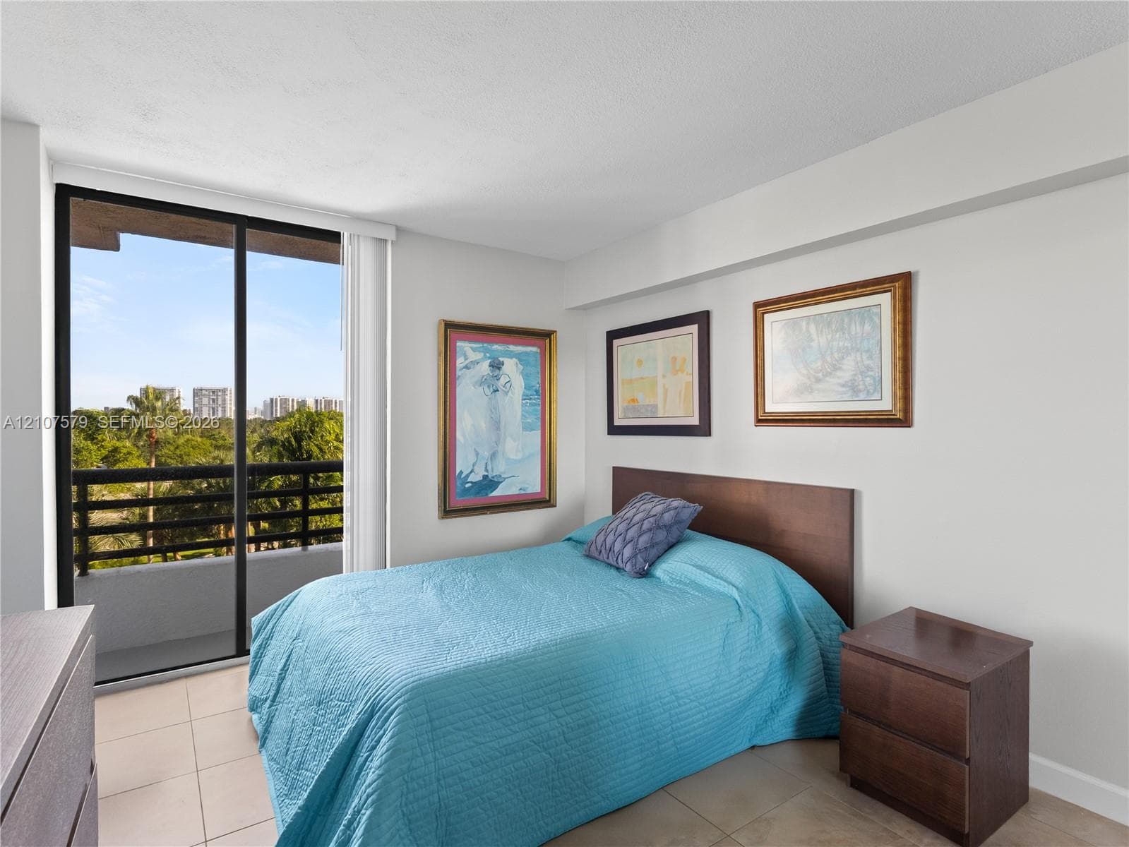 Neutral-tone interior space featuring floor-to-ceiling sliding glass doors, neutral tile flooring, and a private balcony with horizontal railing
