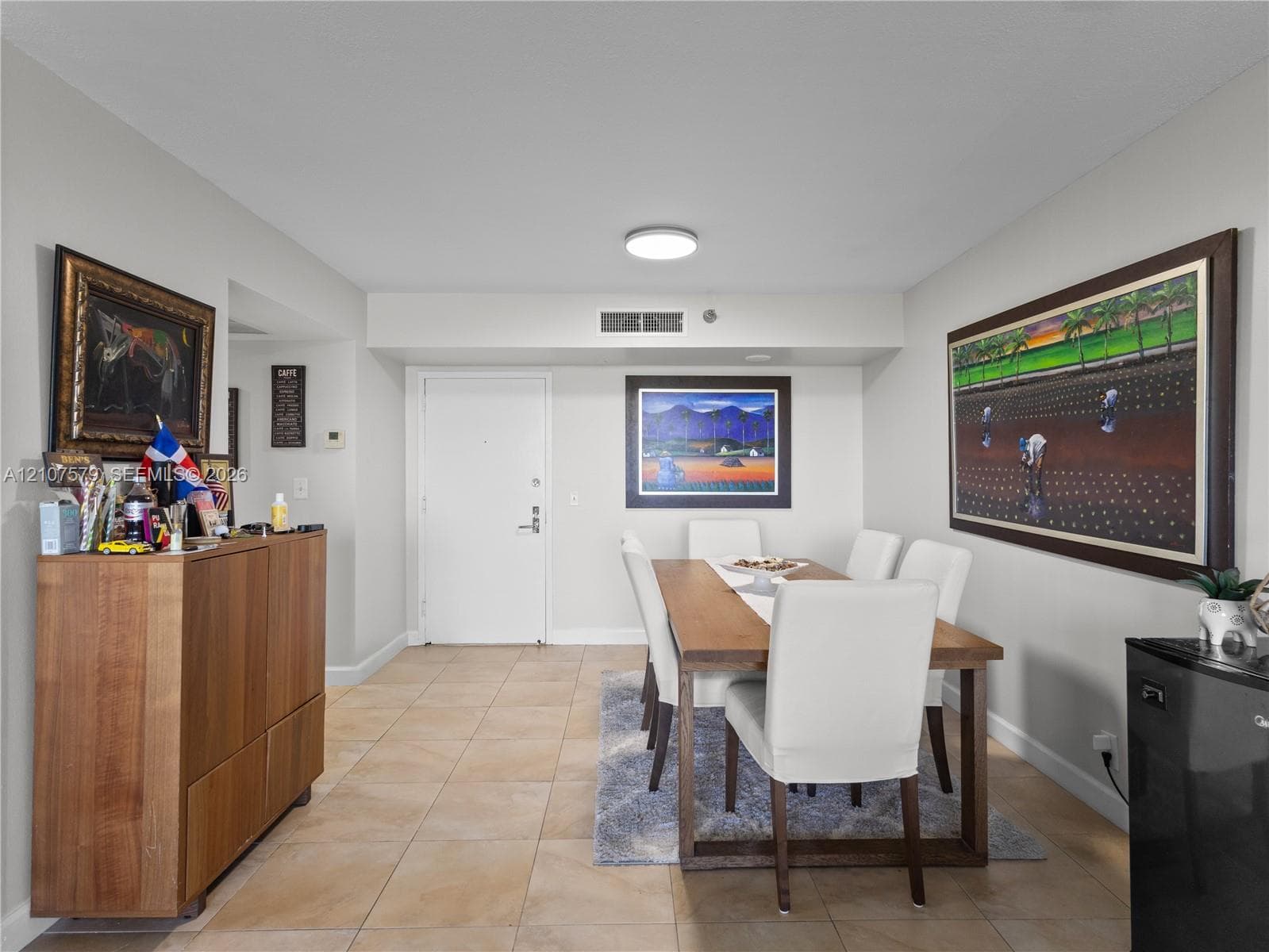 Neutral-toned interior space featuring light-colored ceramic tile flooring, a flush-mount ceiling light fixture, and a solid-core entry door