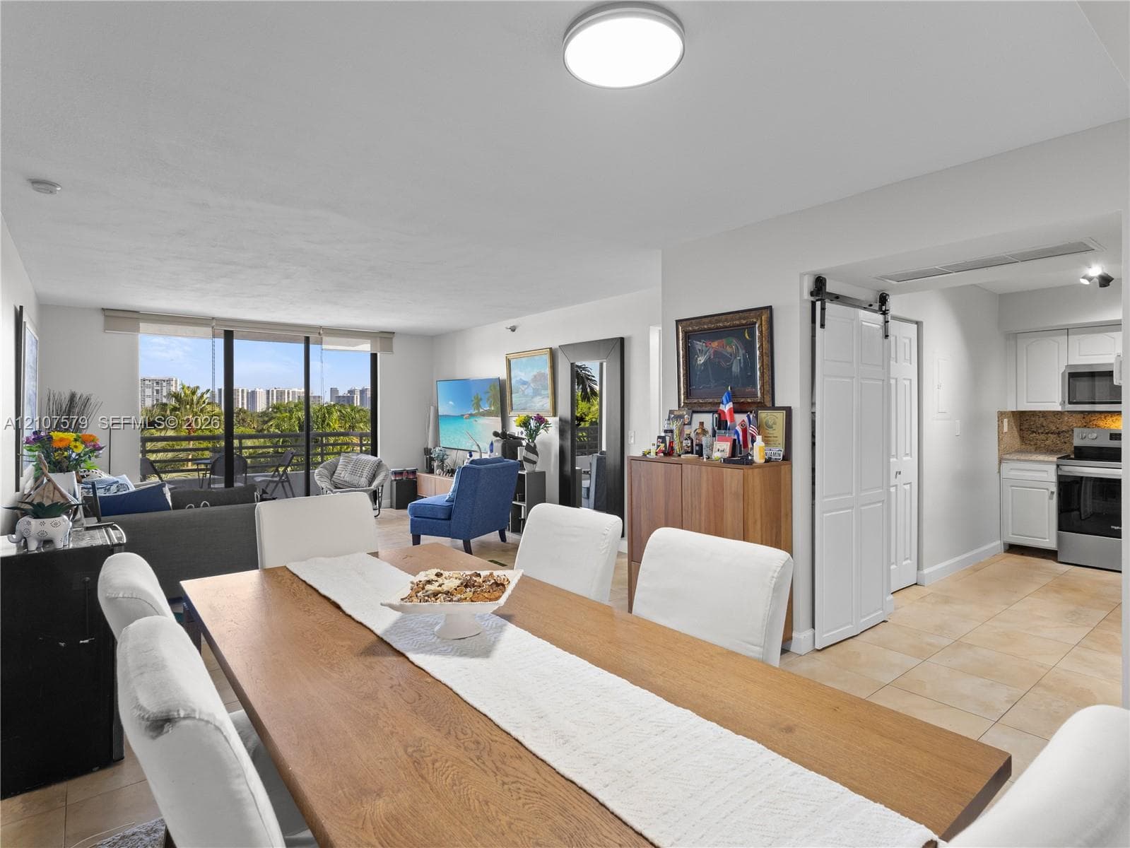 Interior featuring tile flooring, a white sliding barn door, and a full-height glass balcony enclosure