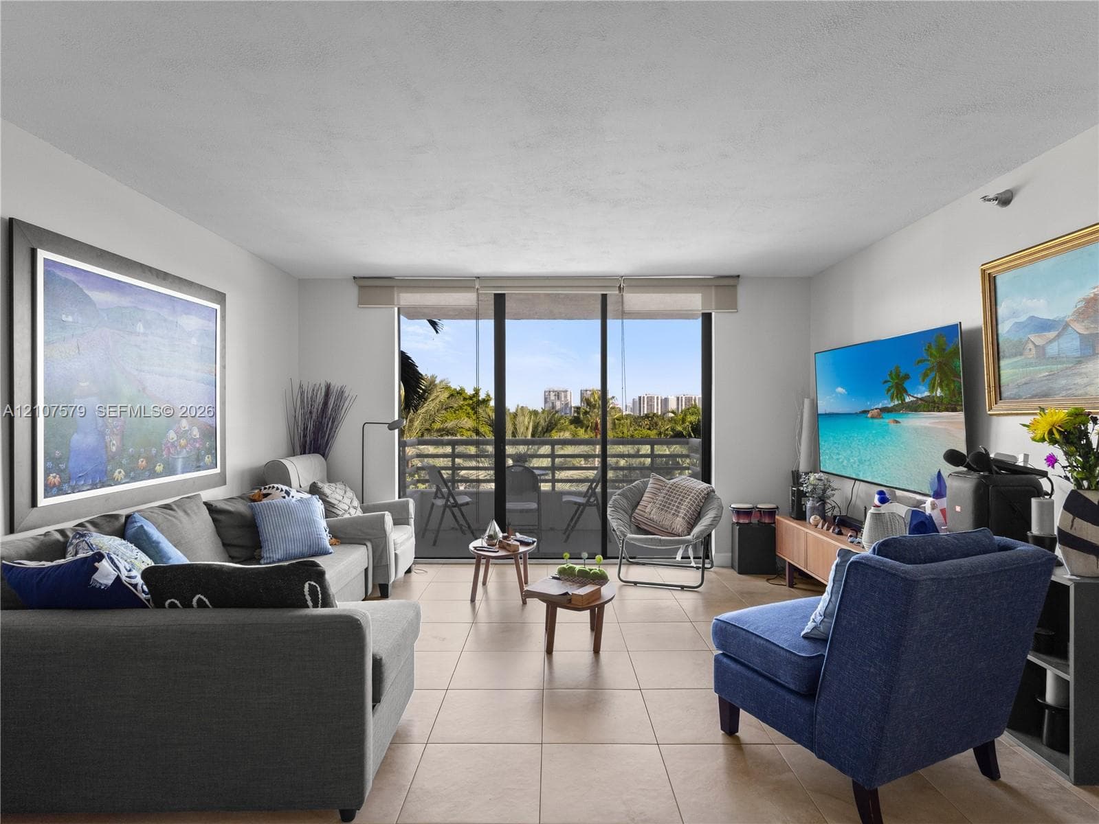 Living area featuring neutral ceramic tile flooring and floor-to-ceiling sliding glass doors opening to a private balcony