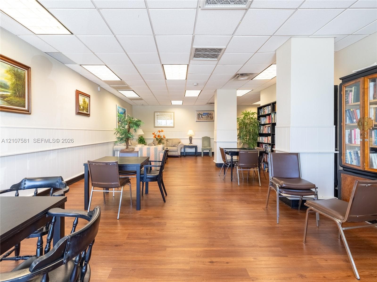 Wood-finish flooring throughout, white wainscoting, recessed lighting, and built-in shelving